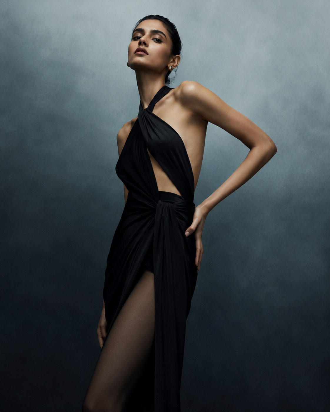 Woman in a black draped cutout gown against a moody backdrop