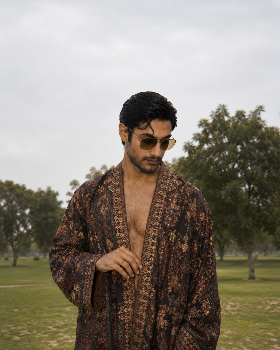 Man in a paisley robe and aviators in a park
