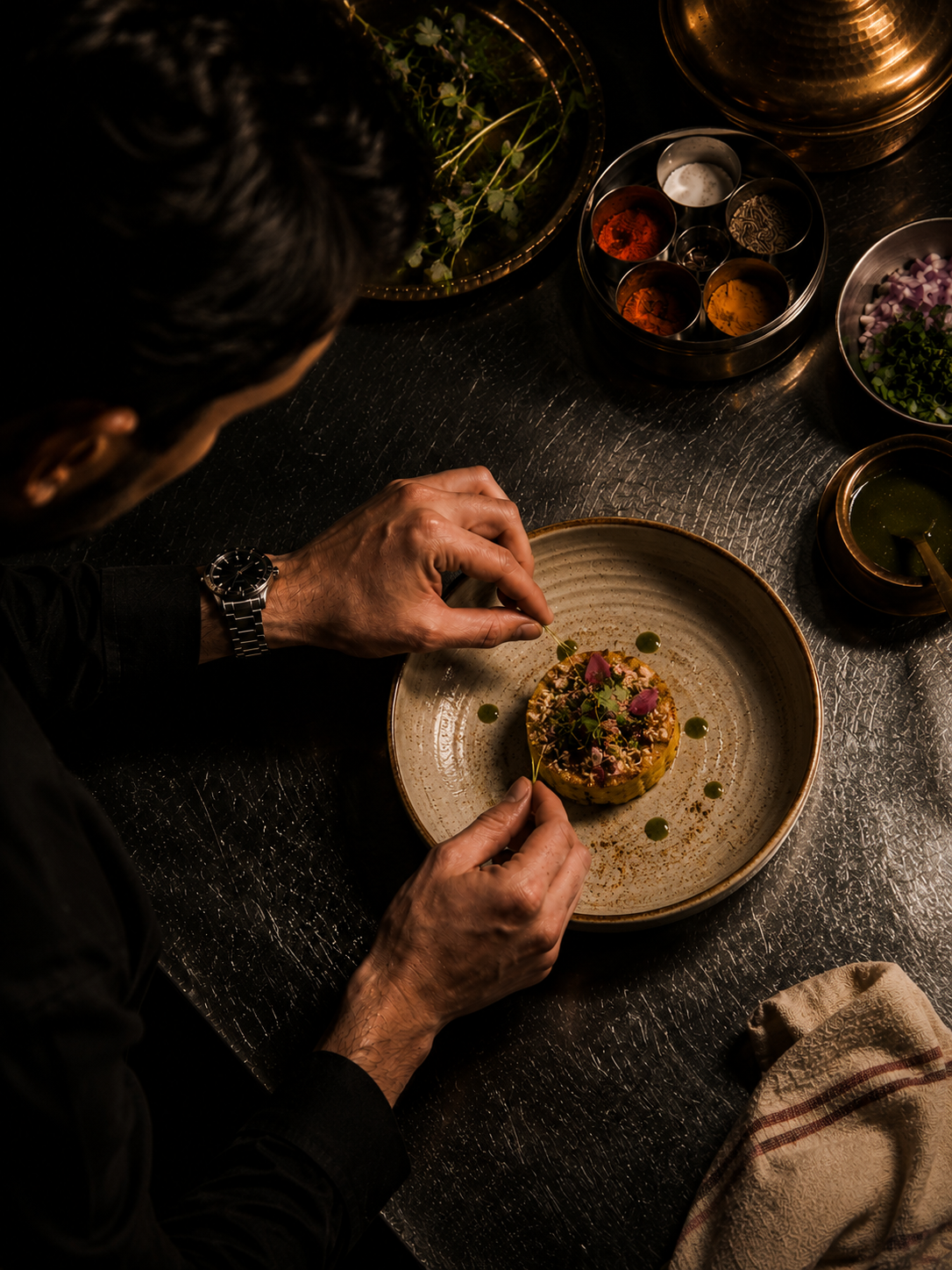 Chef plating a dish beside a masala spice tin